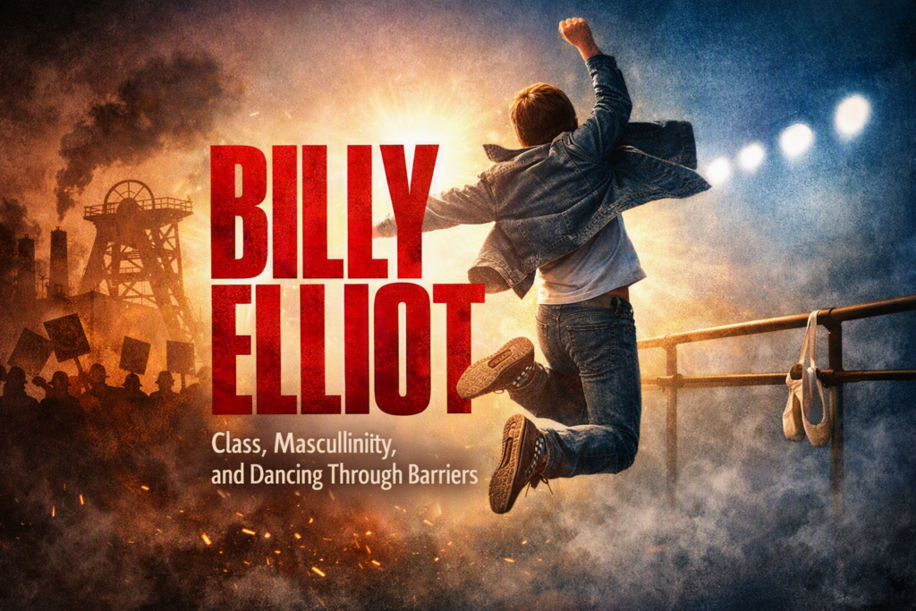 A promotional image for the Billy Elliot musical shows a young boy leaping joyfully between an industrial mining town and a ballet studio. The title “BILLY ELLIOT” appears in bold red letters above him, with the tagline “Class, Masculinity, and Dancing Through Barriers” below. Warm light glows around the boy as he jumps, symbolizing hope and rebellion through dance.