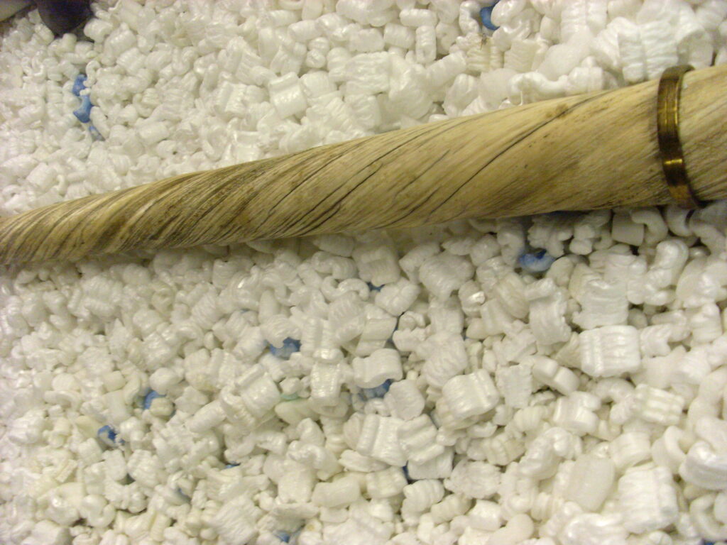 A narwhal swimming underwater in the Arctic with its long spiraled tusk visible as it glides through deep blue water.
